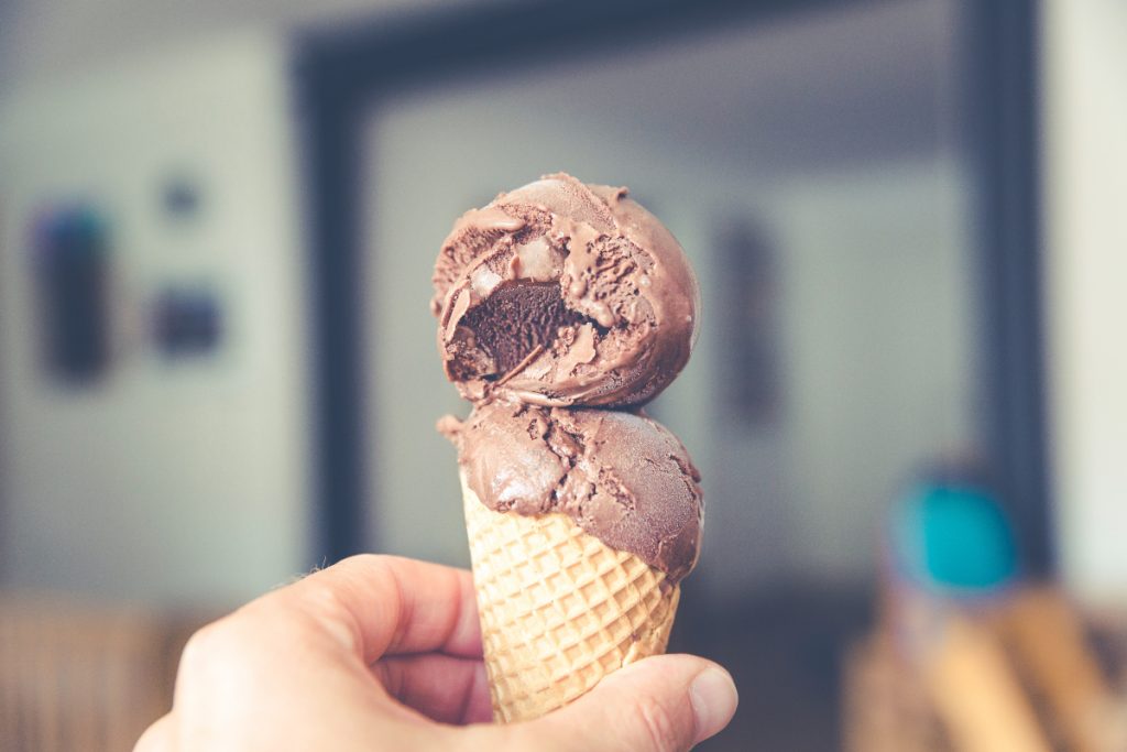 Image of a hand holding an ice cream cone. Dairy is one of many foods that cause inflammation.