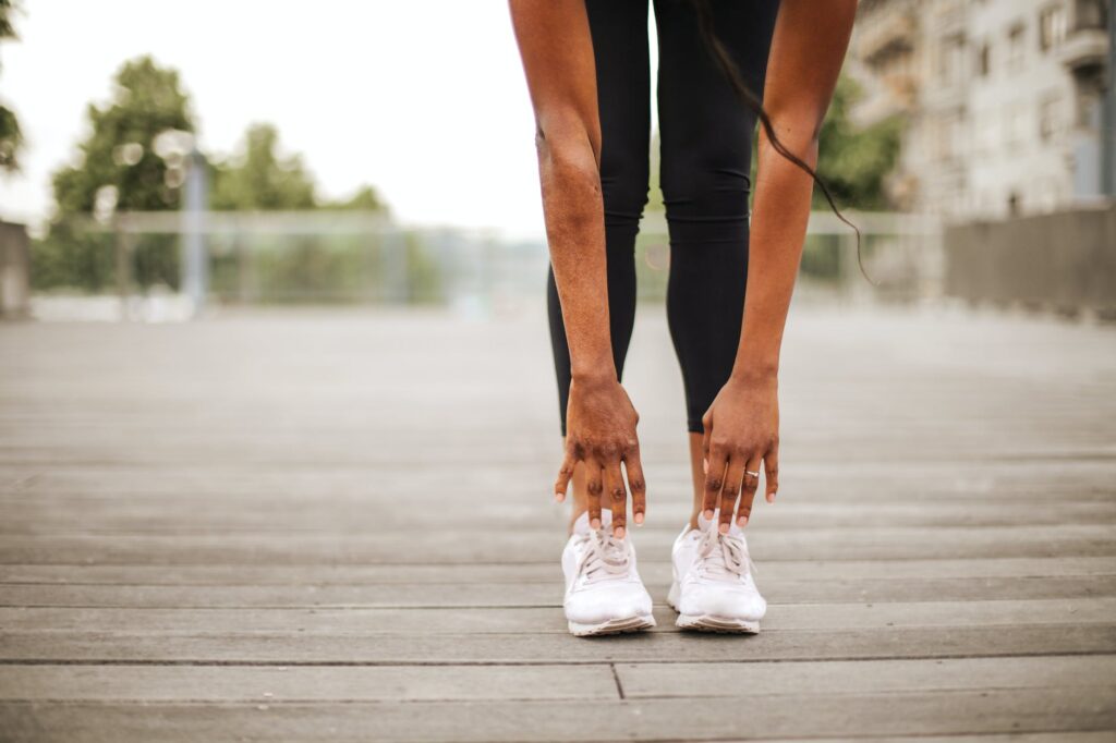 slim woman warming up while training alone on street sports ground